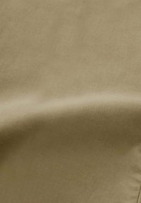Beige Stoff mit glatter Textur und leichtem Glanz, der subtile Farbvariationen und ein weiches, fließendes Aussehen aufweist.