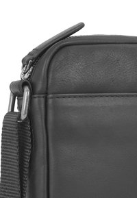 Borsa nera in pelle con superficie testurizzata, dotata di una cerniera metallica e un attacco per manico intrecciato, che sottolinea la durabilità dei materiali e del design.