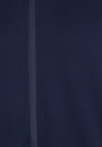 Marineblaues Material mit einer glatten Textur und einem zentralen Reißverschlussdetail. Der Stoff ist weich und leicht, perfekt für legere Kleidung.