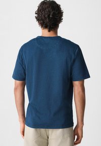 Krátkozrý sleeve navy modré tričko s kulatým výstřihem, měkkou strukturou a volným střihem. Viditelné švy na límci a lemu.