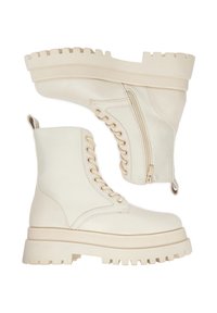 Beżowe, sznurowane buty wojskowe z grubą podeszwą z bieżnikiem, zamkami błyskawicznymi po bokach i pętlami z tyłu, pokazane z widoków bocznego i dolnego.