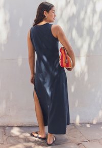 Tumesinine varrukateta maksikleit külgavaustega ja siledast materjalist, mida on kombineeritud mitmevärvilise heegeldatud kotiga ja plätudega.