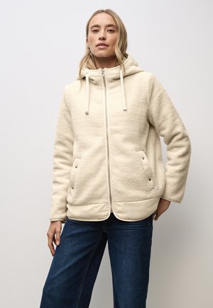 Veste en polaire de couleur crème avec surface texturée, fermeture éclair à l'avant, capuche et ourlet élastique. Dispose de deux poches latérales avec fermetures à pression.