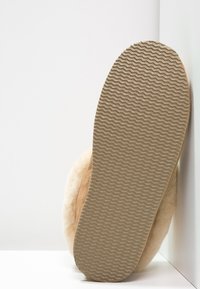 Scarpa slip-on in pelle marrone con suola in gomma beige strutturata, che presenta un bordo liscio e dettagli sulla suola per aderenza e trazione.