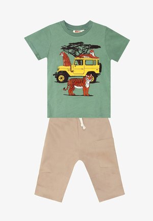 T-shirt verde in cotone con grafiche di tigri e un camion vintage giallo, abbinato a pantaloni cargo beige con tasche laterali e coulisse.
