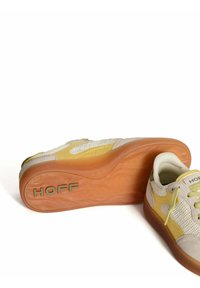 Zapatillas con parte superior de malla beige y acentos amarillos, suela de goma y detalles cosidos. Nombre de marca "HOFF" impreso en el talón.