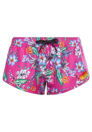 Short de bain rose à motif floral avec des feuilles et fleurs tropicales vertes, blanches, bleues et orange, doté d’un cordon noir et d’une petite étiquette orange.
