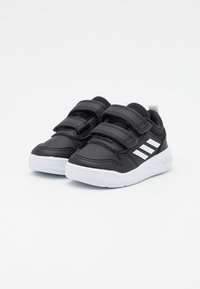 Zapatillas negras con tres franjas blancas, correas de velcro, una parte superior texturizada y una suela blanca. Diseñadas para comodidad y fácil uso.