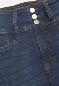 Mörkblå tvättade jeans med tre metallknappar vid h�ögmidjan, orange sömmar och en klassisk femficksdesign.