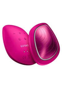 Appareil électronique rose au design arrondi et ovale. Surface lisse, boutons tactiles, et un panneau brillant avec de subtiles rainures. Nom de la marque visible.