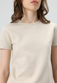 Beige short-sleeve t-shirt made of soft cotton, featuring a classic round neckline and a smooth texture with no visible patterns.