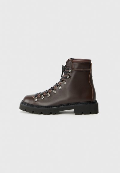 Brown leather hiking boot with silver hardware, lace-up design, padded collar, and thick black rubber sole. Reinforced stitching visible.