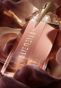 Bouteille de parfum au design rectangulaire élégant en rose doré et matériaux transparents. Équipée d'un capuchon doré et d'un sommet sculptural.