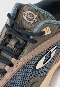 Γκρι και μπλε αθλητικό παπούτσι με υλικά από δίχτυ και δέρμα, διαθέτει επενδυμένη γλώσσα, έντονες ροζ λεπτομέρειες και ευδιάκριτο λογότ υπο στη πλευρά.