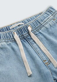 Lichtblauwe denimshorts met een elastische taille, witte trekkoord en een label met de tekst "Gemaakt van gerecycled materiaal."