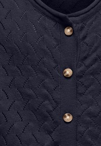 Mornarsko modra pletena cardigan jakna z teksturirano zigzag vzorcem, ki ima okroglo izrez in svetlobno obarvano zapiranje z gumbi spredaj.