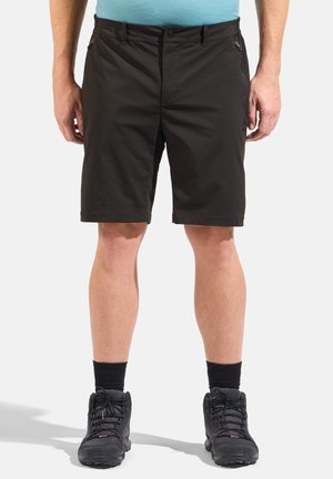 Svarta shorts i lätt tyg med en slät textur, med sidofickor och knäppning, bärs med svarta vandringsskor.