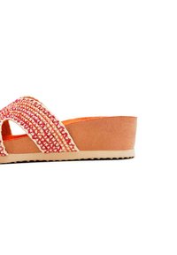 Infradito intrecciato con una fascia texturizzata rosa e crema, un morbido interno arancione e una suola piatta beige con fondo texturizzato.