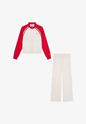 White track jacket with red sleeves and matching white pants, featuring small Champion logos on the chest, sleeve, and pants waistband.