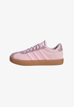 Pink suede sneaker featuring three white stripes, textured pink accent on the heel, and a gum rubber sole. Classic low-profile design.