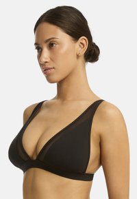 Schwarzer Dreiecks-BH mit transparenten Mesh-Einsätzen, breiten Unterbändern und verstellbaren Trägern für einen unterstützenden Sitz. Glatte Textur und minimalistisches Design.
