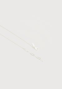 Ασημένιο κολιέ αλυσίδας με διάφορα μεγέθη κρίκων, συμπεριλαμβανομένων επιμηκυμένων οβάλ κρίκων και κούμπωμα με κλειδαριά καβουριού, σε απλό λευκό φόντο.