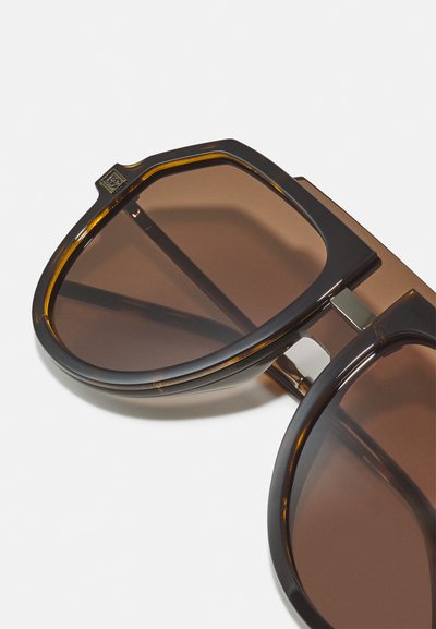 Brown tinted sunglasses with a thick, dark tortoiseshell frame, featuring a dual lens design and metallic hardware accents.