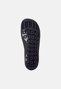 Sola di scarpa in gomma nera caratterizzata da modelli di presa circolari, scanalature e nome del marchio impresso, progettata per trazione e stabilità.