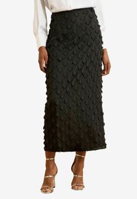 Jupe midi noire avec un motif floral texturé et une coupe droite. Confectionnée dans un tissu à la finition lisse et à l'éclat subtil.