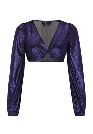 Vijolični kratek top z globokim V-izrezom, dolgimi okroglimi rokavi in krožno okrasno tačko na sredini. Tkanina se zdi sijoča z teksturiranim zaključkom.