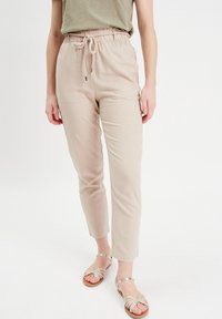 Pantalons beige coupe décontractée avec un waistband élastique et un cordon de serrage. Fabriqués en tissu léger, dotés de poches latérales et d'une texture lisse.