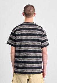 Sort og hvid stribet kortærmet t-shirt med en afslappet pasform, der har et struktureret mønster og en rund halsudskæring.