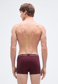 Vinröda boxerkalsonger med svart resårmidja med vit text "JACK & JONES", mjukt bomullsmaterial och figurnära passform.