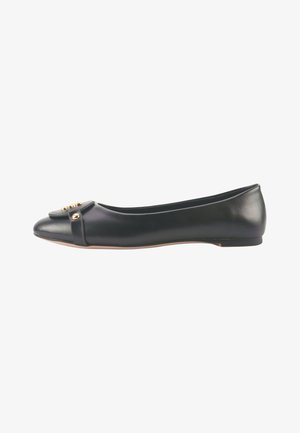 Zapato plano de cuero negro con punta redondeada, detalle de lazo acentuado y herrajes en tono dorado. Textura suave y diseño minimalista.