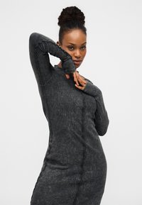 Φόρεμα με μακριά μανίκια, εφαρμοστό, από σκούρο γκρι ριπ ύφασμα. Διαθέτει περίπλοκες ραφές και τρύπες για τον αντίχειρα στις άκρες των μανικιών για επιπλέον στιλ.