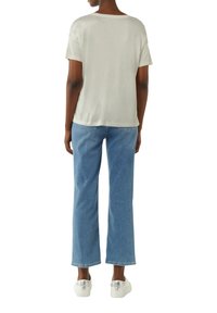Light gray short-sleeve t-shirt paired with medium blue, straight-leg jeans. Model wears white sneakers with a transparent accent.