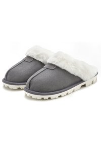 Gray suede slippers with white faux fur trim, featuring a rounded toe and textured white rubber sole for grip. Soft and warm design.