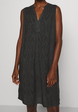 Vestido negro sin mangas con un sutil patrón de piel de serpiente, escote en V, llevado por una persona con piel morena y un collar delgado con un pequeño colgante.