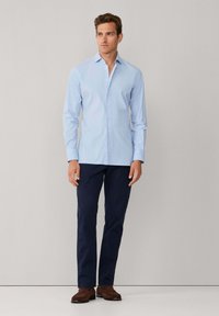 Lichtblauw overhemd met lange mouwen en een button-down kraag, slim fit, gecombineerd met marineblauwe broek. Het overhemd heeft een subtiele textuur.