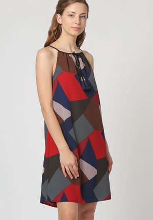 Vestido sin mangas colorido con patrones geométricos en rojo, azul, gris y marrón, con un lazo en el cuello y detalle de borlas. Hecho de tejido ligero.