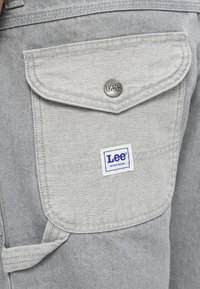 Pantaloni scurți de lucru din denim gri, cu un buzunar cu clapetă, un nasture metalic argintiu și un patch cu logo-ul albastru "Lee Workwear". Material texturat și design utilitar.