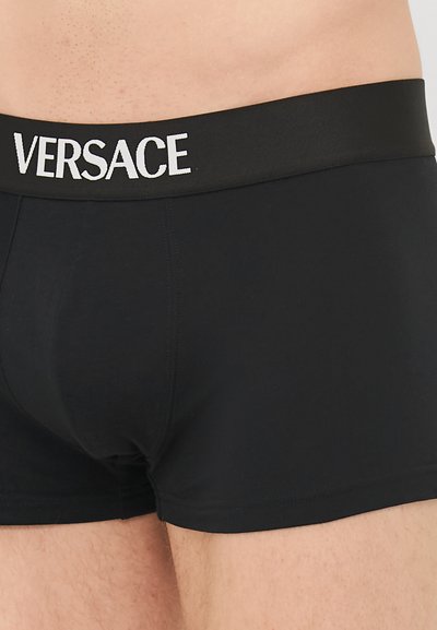 Sorte bomullsboxer med bred svart midjebånd som har hvit "VERSACE"-logo. Fitted design med glatt tekstur og ingen synlige mønstre.