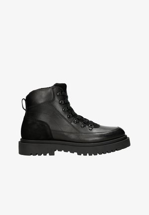 Stivali neri in pelle sopra la caviglia con una finitura liscia, punta rotonda, sistema di allacciatura visibile e suola con battistrada robusto. Presentano un accento in suede sul tallone.