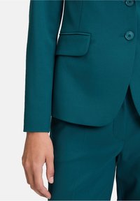 Teal blazer met een enkele borstontwerp. Bevat drie knopen en een borstzak, gemaakt van een gestructureerde stof. Getailleerde snit.