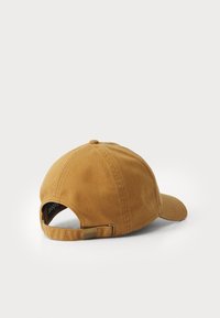 Casquette de baseball en coton marron avec une visière courbée, une sangle réglable à l'arrière et une petite étiquette logo sur la bande intérieure.