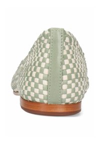 Platta skor med ett vävt mönster i grönt och vitt, läderdetaljer vid hälen och sidorna, och en trädsula.