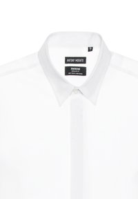 Camisa blanca de mangas largas con cuello abotonado, hecha de una suave mezcla de lino. Presenta un corte regular y etiquetas de marca discretas.