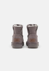 Bottes de cheville en faux suède gris avec une doublure intérieure texturée, un col rembourré et une semelle en caoutchouc. Présente un patch logo marron à l'arrière.