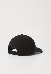 Black cotton baseball cap with a curved brim, adjustable strap at the back, and embroidered logo. Textured fabric with ventilation holes.