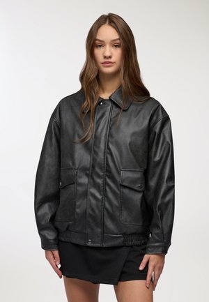 Giacca in pelle sintetica nera con colletto a punta, due tasche frontali e orlo arricciato. Tessuto morbido e vestibilità leggermente oversize.